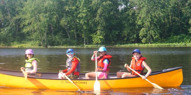 Young children paddling a yellow recreational canoe