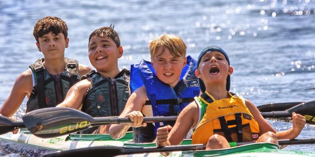 Four boys in a kayak celebrating after their race