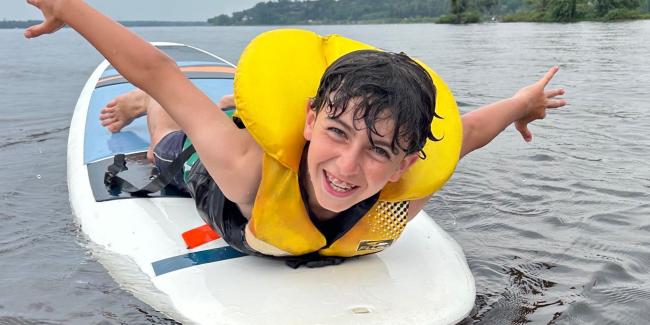 Smiling boy on his belly, floating on a stand up paddleboard