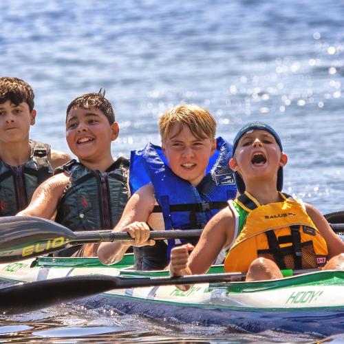 Four boys in a kayak celebrating after their race